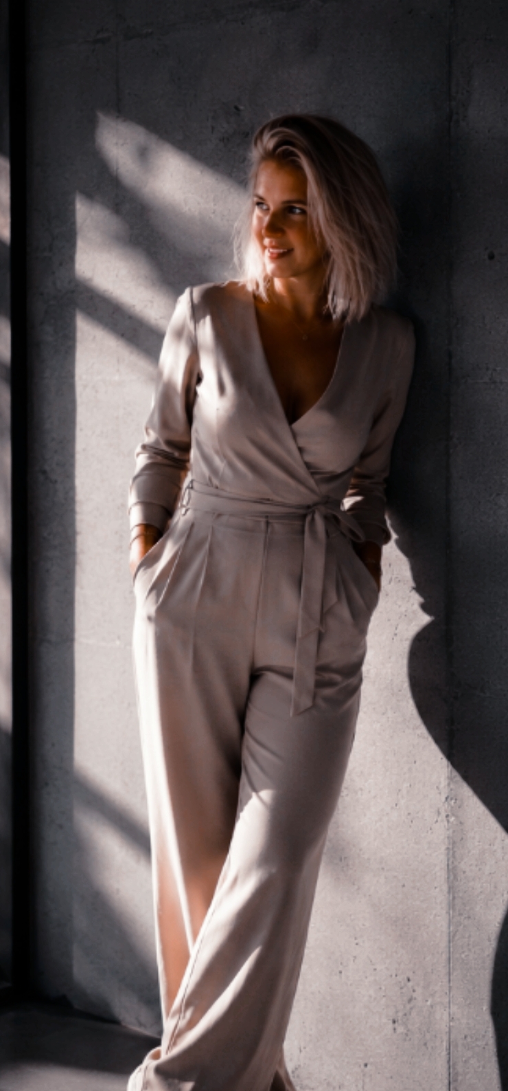Julia Gierzinger im beigen Jumpsuit vor einer Betonwand